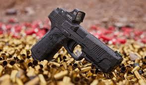 Daniel H9 Pistol Resting on Bullet Shell Casings – Liberty Arsenal Daniel H9 9mm pistol displayed on a bed of spent bullet shell casings, highlighting its bold, modern design and tactical appeal.